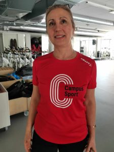 A smiling woman who wears a red CampusSport shirt.