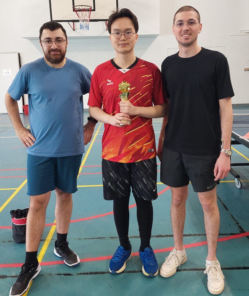 Pöytätenniskilpailujen voittajat ryhmäkuvassa Iskerin liikuntasalissa. Voittaja pitelee palkintoa.